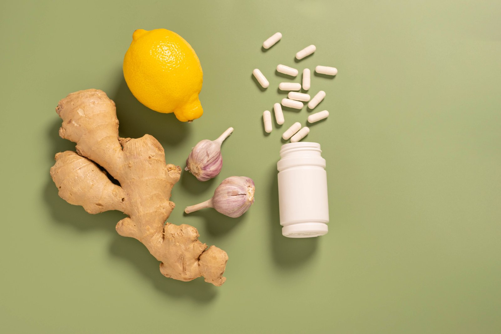 Fresh ginger root lemon garlic jar with vitamin pills on green background, minimalism. The concept of alternative medicine, nutritional supplements, ayurveda, natural medicines . Top view flat lay